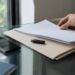 Una mano guarda un informe forense sobre blockchain dentro de una carpeta.